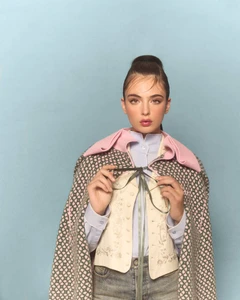Model Deva Cassel wearing patterned cape and embroidered vest against blue backdrop for Harper's Bazaar Turkey