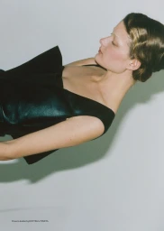 Profile view of a woman wearing a black sleeveless leather top against a plain light background.