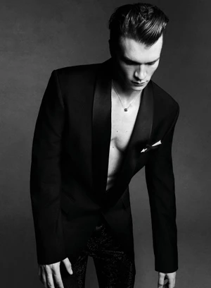 Portrait of Connor Storrie wearing a black tuxedo jacket with no shirt in a monochrome editorial studio shot for V Man