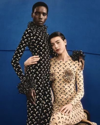 Two female models in printed crescent bodysuits posing against a solid blue background for Marine Serre Fall 2026.