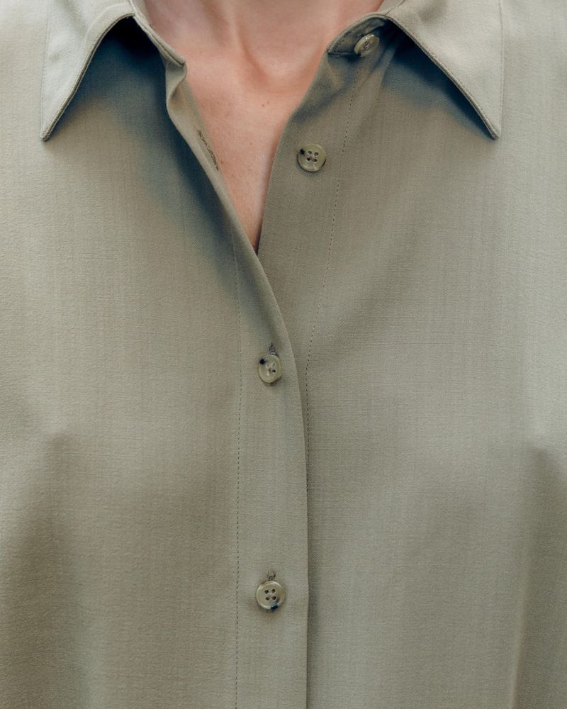 Close-up portrait of a person wearing a sage green button-down shirt for the Harvey Nichols campaign.