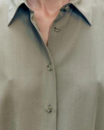 Close-up portrait of a person wearing a sage green button-down shirt for the Harvey Nichols campaign.