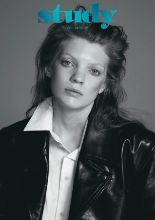 Black and white magazine cover featuring a model in a black leather jacket and white collared shirt against a gray backdrop.