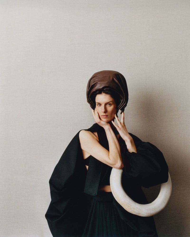 Model Marte Mei van Haaster wearing a dark headpiece and black garment holding a white ring for M Le magazine du Monde