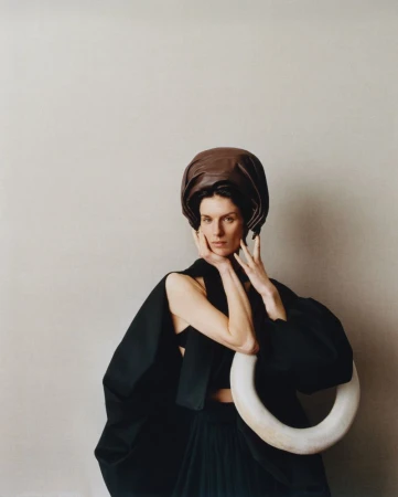 Model Marte Mei van Haaster wearing a dark headpiece and black garment holding a white ring for M Le magazine du Monde