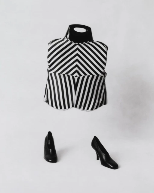 Black and white striped top on a mannequin stand with black high heels on a white background in a studio setting, fashion shot.
