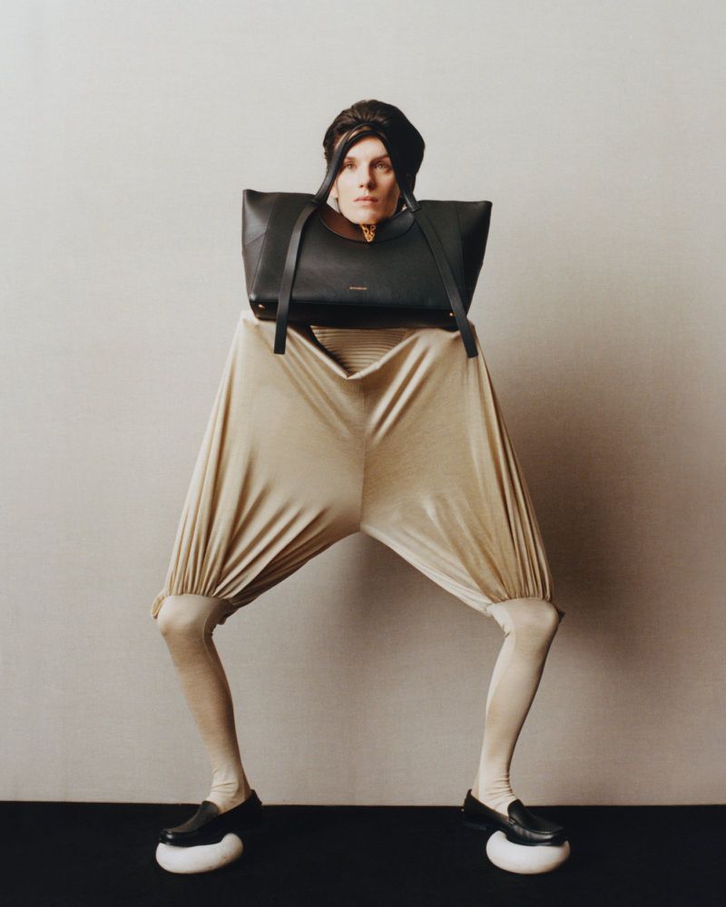 Model Marte Mei van Haaster wearing avant-garde sculptural garments with a large black handbag framing her head for M Le magazine du Monde