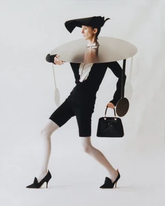 Model Marte Mei van Haaster wearing a sculptural metallic neckpiece and black hat in an editorial by David Luraschi.