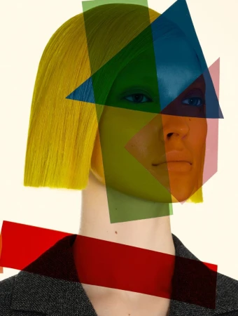 Woman with yellow hair and geometric color filters posing in a studio with a grey jacket and neutral background for a fashion editorial.