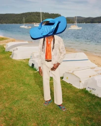 Surreal fashion image of a man standing by a beach wearing a giant blue flip-flop over his head for Havaianas Summer 2024 campaign.
