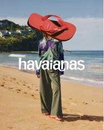 Surreal commercial campaign image featuring a large red flip-flop replacing a person's head on a sandy beach.
