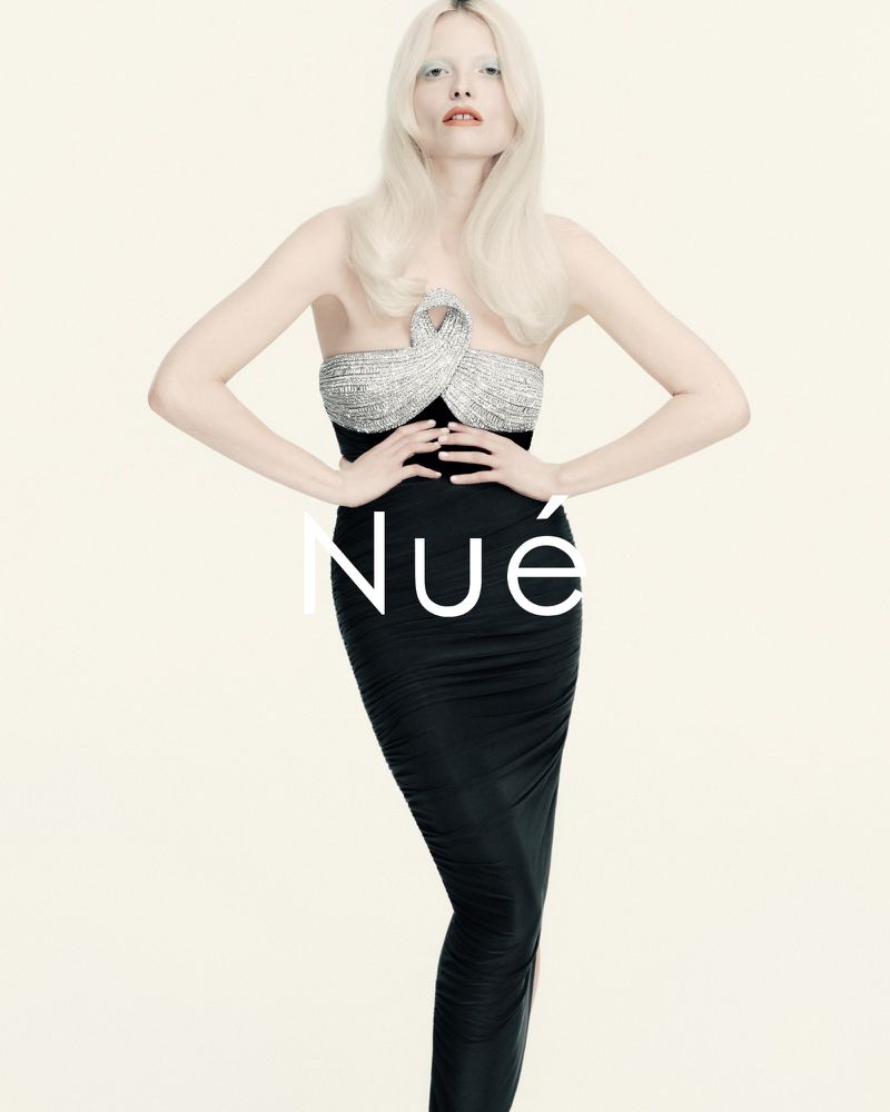 Model with long blonde hair wearing a black strapless gown with a sparkling crystal bodice against a white background.