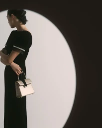 Model in black dress holding a metallic handbag framed by a circular spotlight for Prada Ramadan 2026