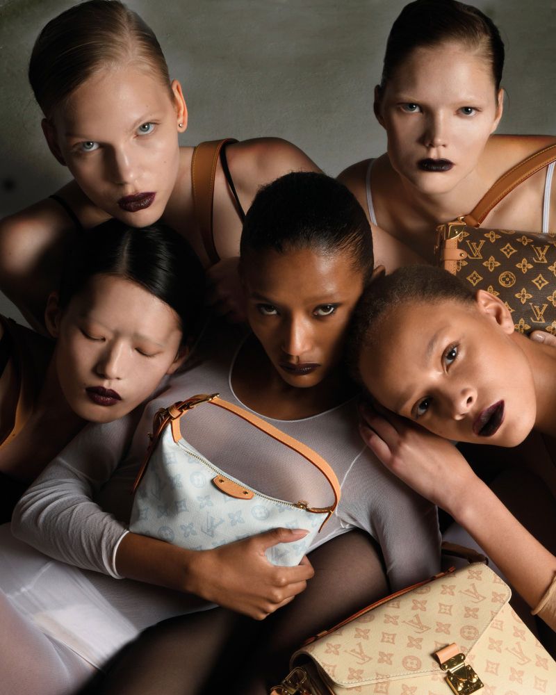 Five fashion models pose with a collection of Louis Vuitton monogram handbags in a studio setting, showcasing edgy makeup and creative direction.