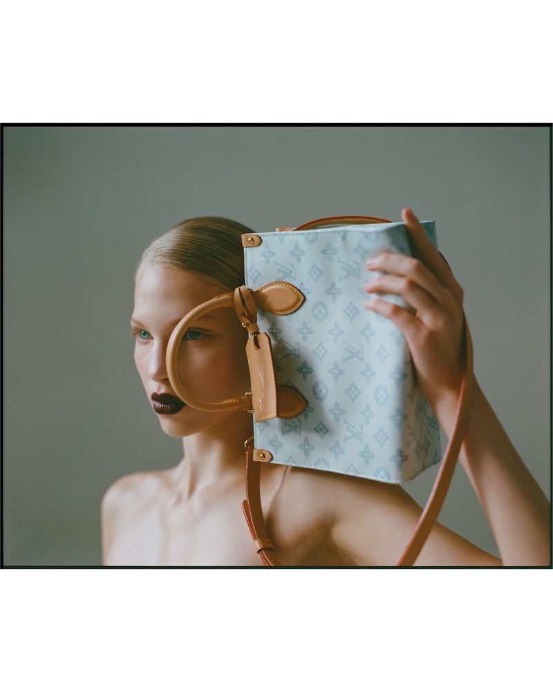 Model poses in a studio with a light blue Louis Vuitton box bag with tan leather trim and handle, featuring dark red lipstick.