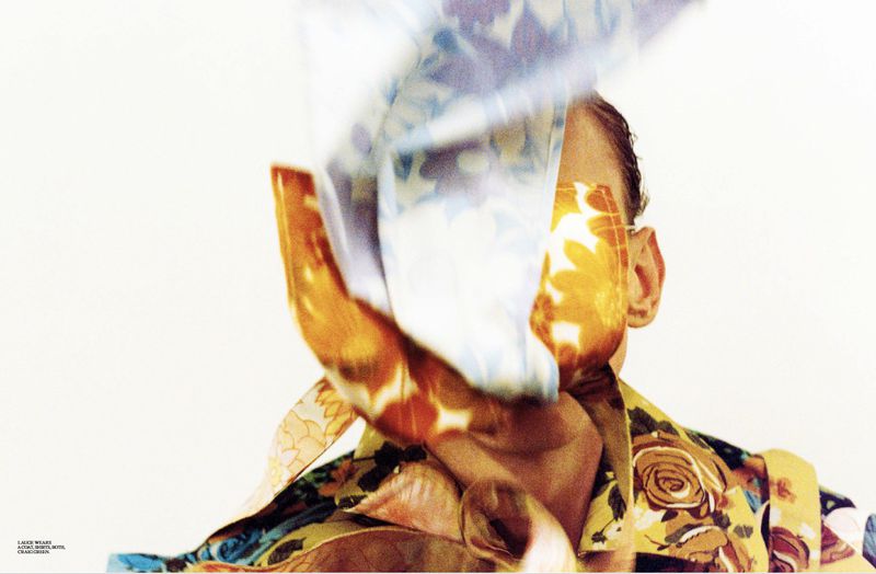 Abstract fashion shot featuring a person's face partially obscured by a floral print garment against a clean, bright, white backdrop.