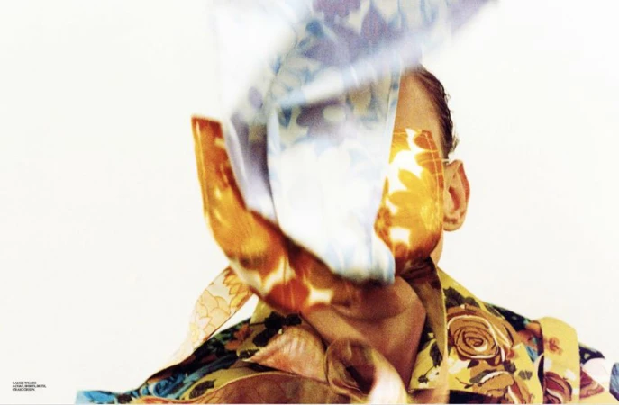 Abstract fashion shot featuring a person's face partially obscured by a floral print garment against a clean, bright, white backdrop.