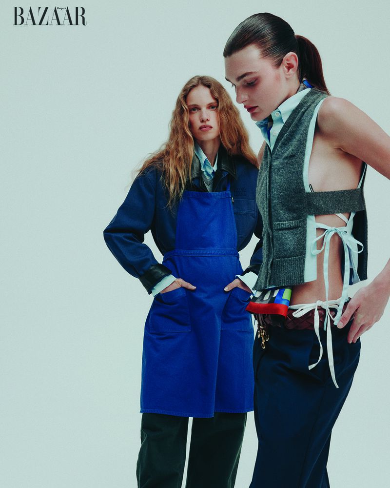 Two fashion models pose in a photo studio wearing contemporary workwear-inspired outfits against a plain white backdrop.