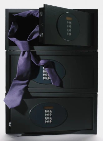 Stack of three black safes with digital keypads, the top safe open, with a purple necktie draped across the safes.