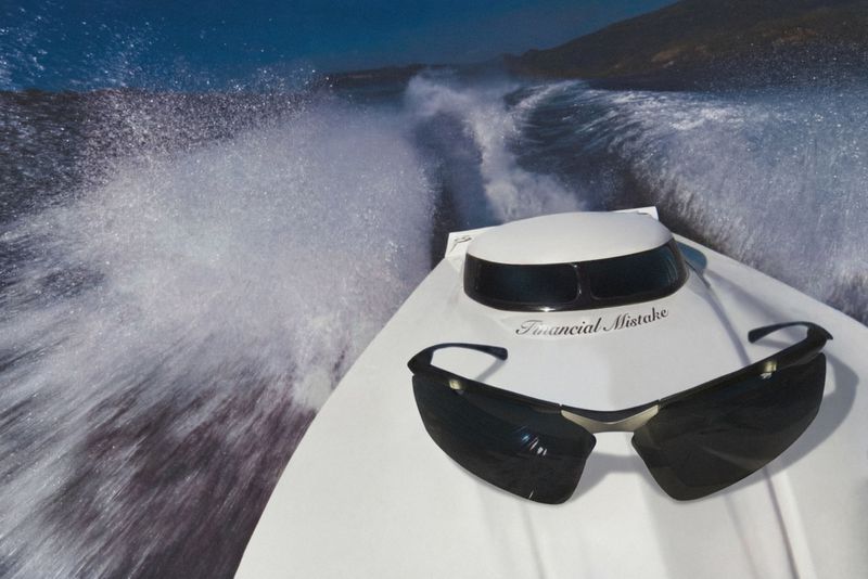 High-speed motorboat cuts through blue ocean water, creating white wake with sunglasses and a light reflection on the deck.