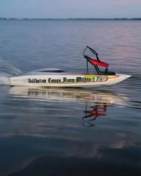 A sleek white motorboat with a high-heeled shoe mounted on deck moving across calm water