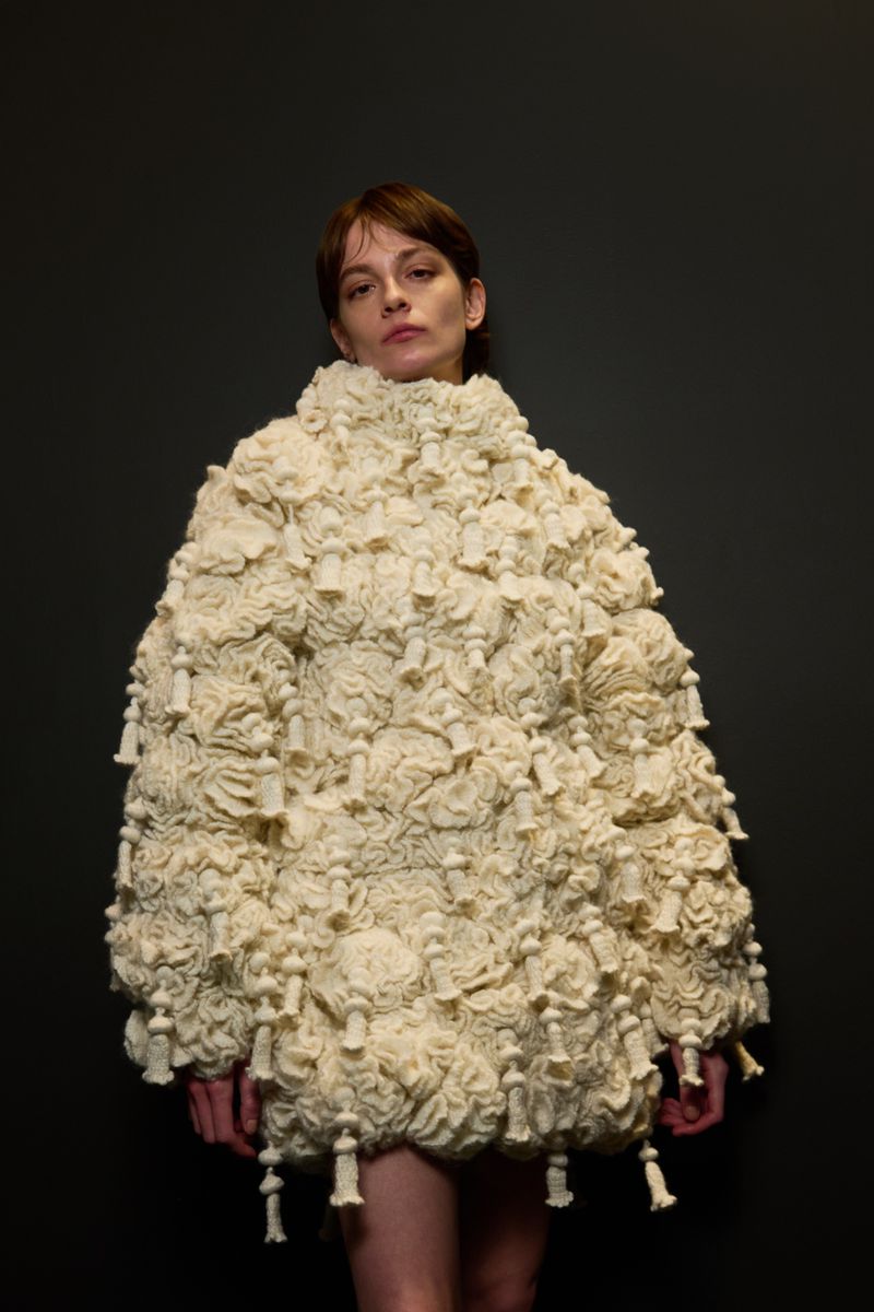 Woman in Avant-Garde Textured Dress: Studio shot of a stylish adult female wearing a unique, sculptural dress with a neutral backdrop.
