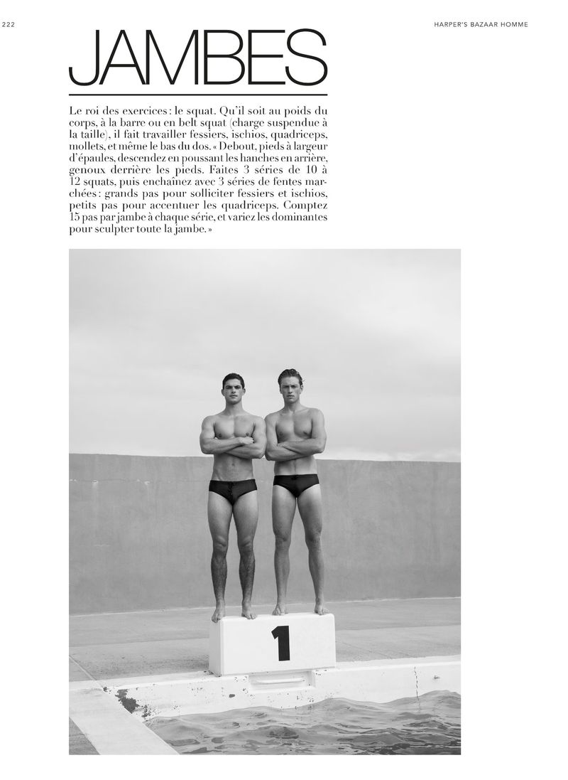 Two muscular men stand on a diving platform in swim briefs. A black and white, medium shot photograph emphasizing male physique and athleticism.