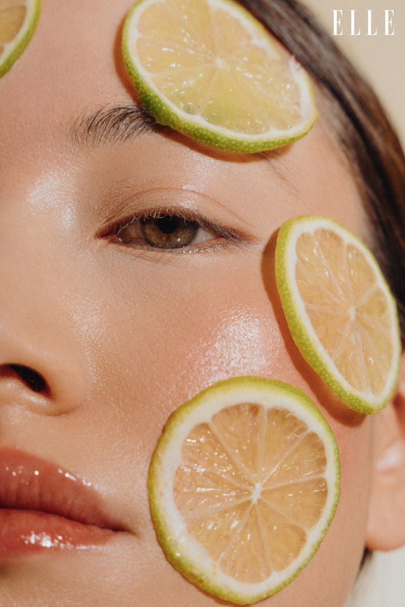 Close-up beauty shot featuring a model's face adorned with citrus fruit slices, highlighting fresh skincare and cosmetic elements.