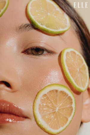 Close-up beauty shot featuring a model's face adorned with citrus fruit slices, highlighting fresh skincare and cosmetic elements.
