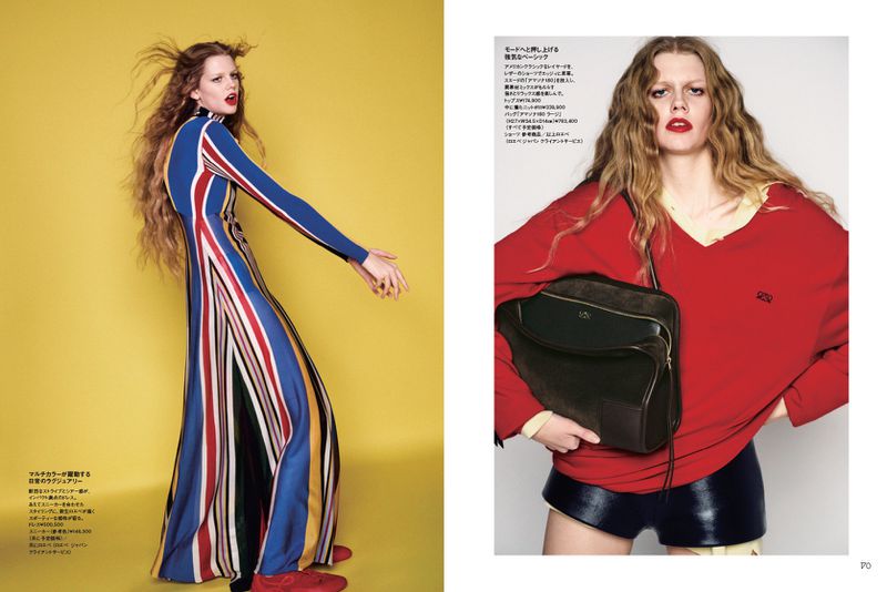 Fashion editorial shot of a female model posing in a full-length, multi-striped dress against a yellow background and red sweater with bag.