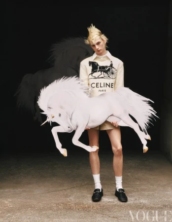 A fashion shot features a young adult holding a unicorn prop, wearing a CELINE sweatshirt, socks, and loafers in a dark studio setting.