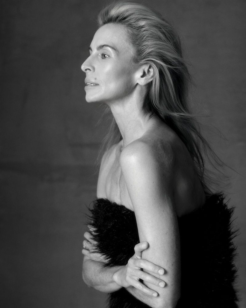 Black and white portrait of an adult woman with light-colored hair in profile, bare-shouldered, partially covered with a black fur wrap.