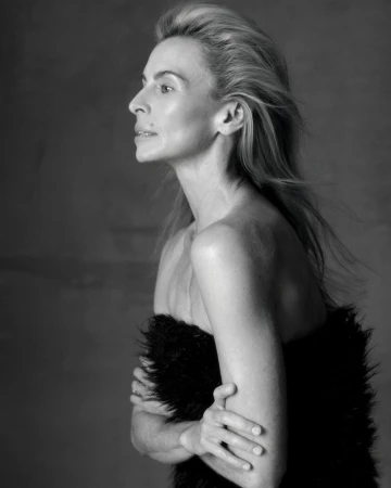 Black and white portrait of an adult woman with light-colored hair in profile, bare-shouldered, partially covered with a black fur wrap.