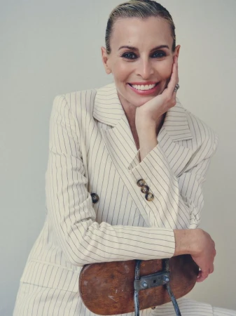Model Niki Taylor smiling with hand to chin wearing a pinstripe suit for Harper's Bazaar Australia editorial.