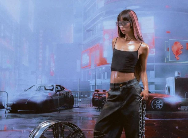 Adult female model with pink-streaked hair in a futuristic urban scene with cars, wearing a black crop top, pants, and silver chain.
