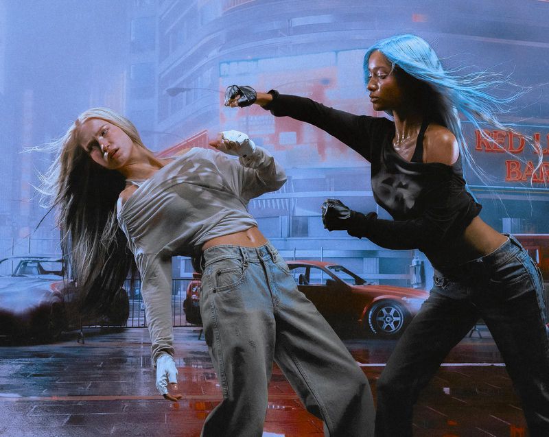 Two women with dyed hair in an outdoor urban fight scene at dusk, wearing casual clothing, with cars and building in background.