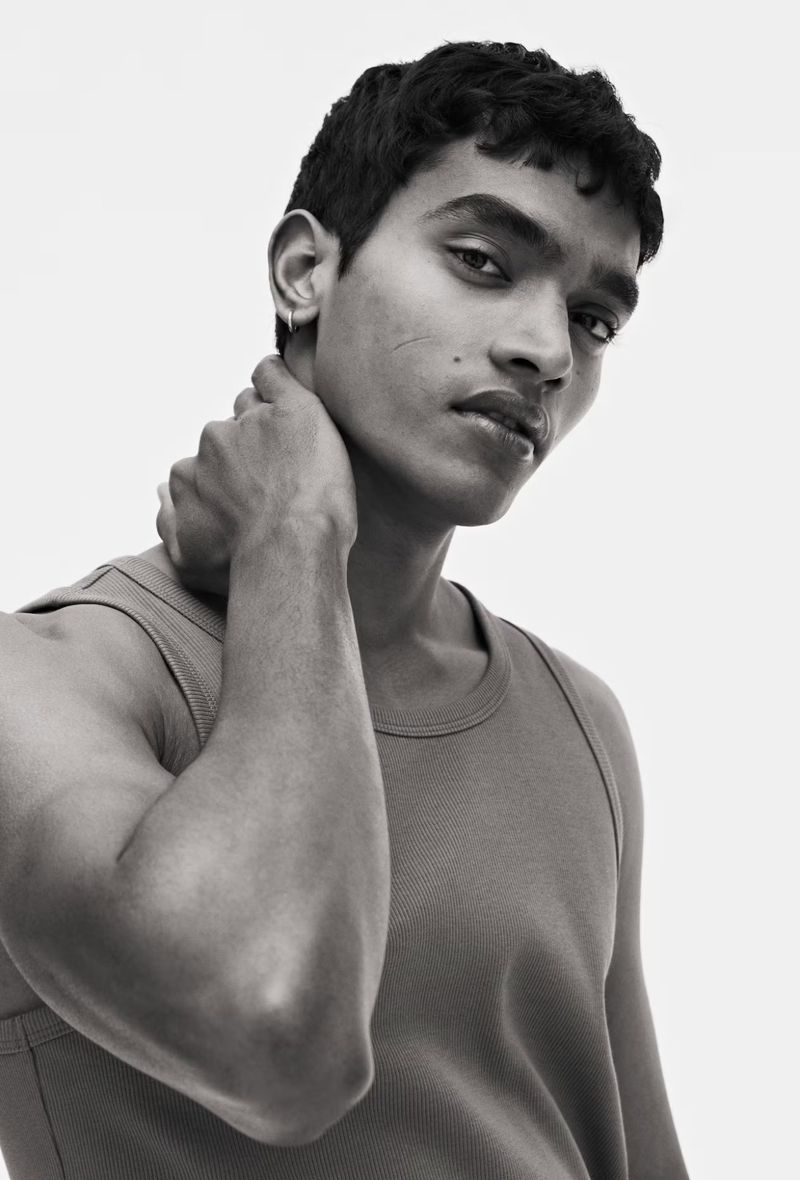 Portrait of a dark-skinned adult male with dark hair, wearing a tank top against a white backdrop, in a black and white photograph.