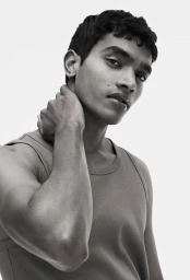Portrait of a man wearing a tank top with hand on his neck against a plain white background