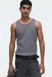 Man wearing a grey tank top and black belt against a bright white background for H and M