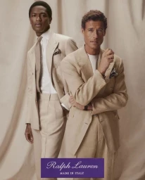 Two men in tailored beige suits posing against a neutral draped fabric backdrop for Ralph Lauren Purple Label