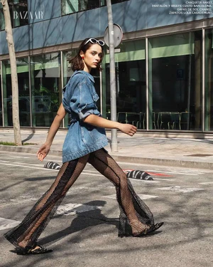 Model in denim jacket and fishnet flared trousers walking outdoors on a city street by David Garcia.
