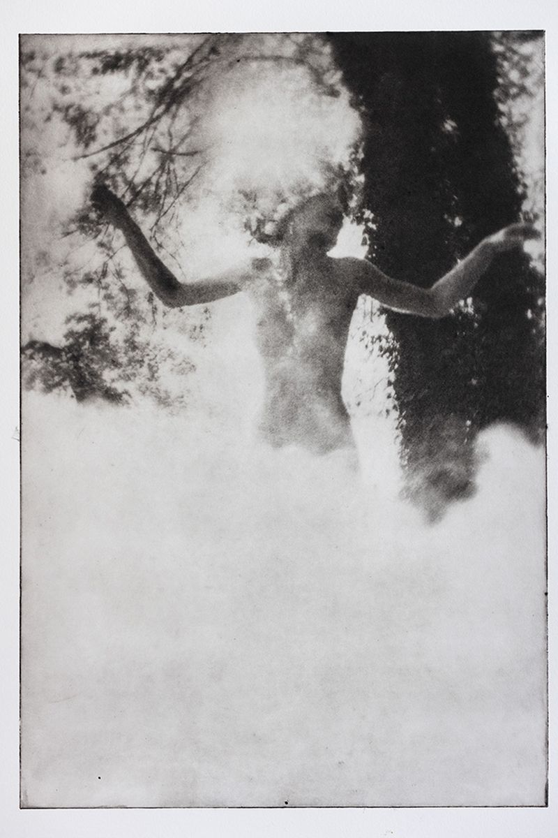 Monochrome artistic portrait of a nude woman with arms raised, standing among trees, showcasing a fine art photography technique.