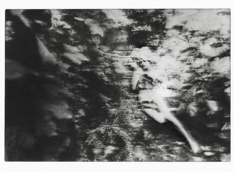 Monochrome fine art image of woman with violin lying amongst leaves in a garden, rendered with soft focus and textured effects.