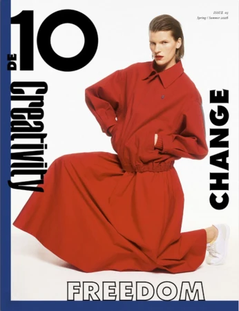 Magazine cover featuring an adult female model in a red jacket and matching skirt, kneeling against a white backdrop with overlaid text.