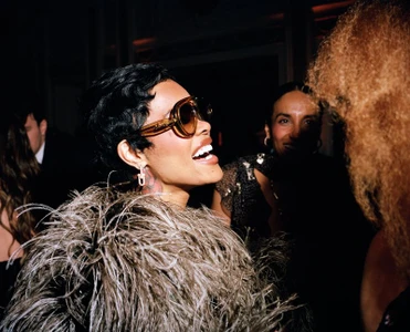 Woman in feathered coat wearing large sunglasses laughing at an event, photographed by Ewen Spencer for British Vogue BAFTAs Portfolio 2026.