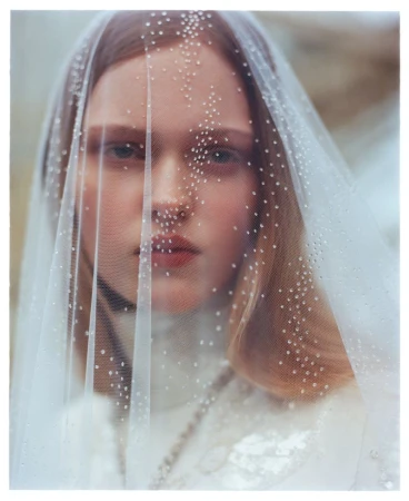 Close-up portrait of model Ava Shipp wearing a sheer embellished veil covering her face for Vogue China