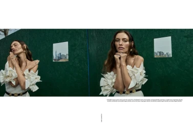 Phoebe Tonkin in a white ruffled off-shoulder dress against a dark green paneled backdrop for Vogue Australia