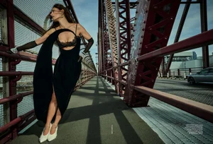 Phoebe Tonkin wearing a black cutout dress and white heels on a red metal bridge for Vogue Australia.