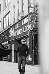 Simon Baker wearing sunglasses and black turtleneck standing on a New York sidewalk for The Blank Page Magazine editorial