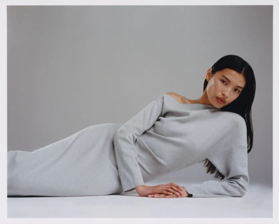 Model in a long grey dress reclining on a white seamless studio backdrop for Revolve